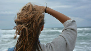 Frau mit wehenden Haaren am Meer