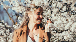 Eine junge Frau steht neben blühenden Bäumen
