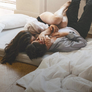 Ein Mann und eine Frau küssen sich auf einem Bett.