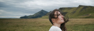 Eine Frau von Angesicht zu Angesicht auf einem Feld mit Bergen im Hintergrund.