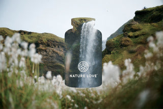Eine Flasche mit der Aufschrift Geschenkgutschein Nature Love vor einem Wasserfall.