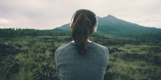 Eine Frau steht auf einem Feld mit Bergen im Hintergrund.