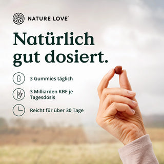 Eine Person hält eine Nuss mit dem Wort Nature Love darauf, während sie Bacillus subtilis Gummies für eine hochdosierte Darmflora konsumiert.
