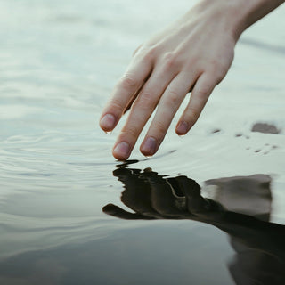 Die Hand einer Person greift ins Wasser.
