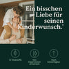 Ein kleiner Junge umarmt seine lächelnde Mutter in einem gemütlichen Zimmer, über ihnen steht ein deutscher Text über Liebe, Familie und „Hey Papa“-Kapseln. Markenname: Nature Love