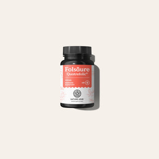 Eine kleine schwarze Flasche „Nature Love Folsäure Quatrefolic® Tabletten“ mit einem weiß-korallenfarbenen Etikett, die 180 vegane Tabletten enthält.
